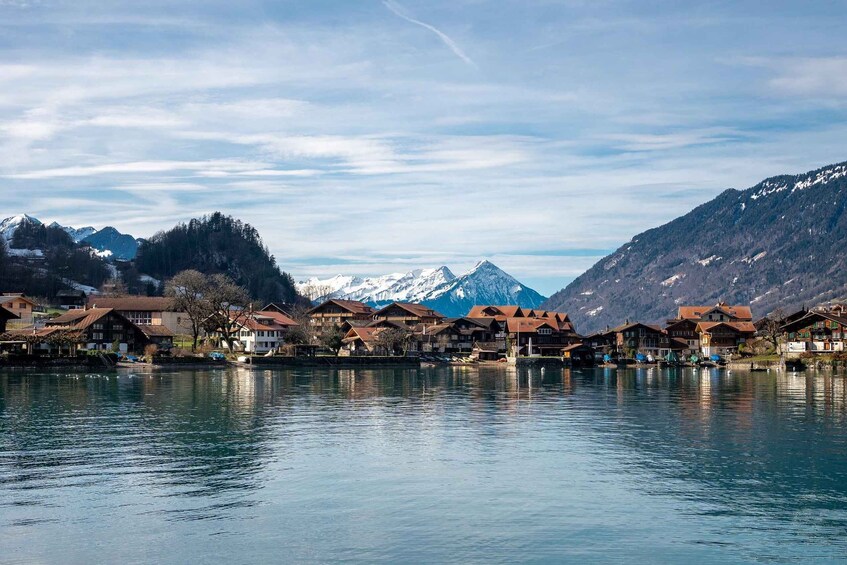 A lakeside village with traditional houses, snow-capped mountains, and a clear sky. 2