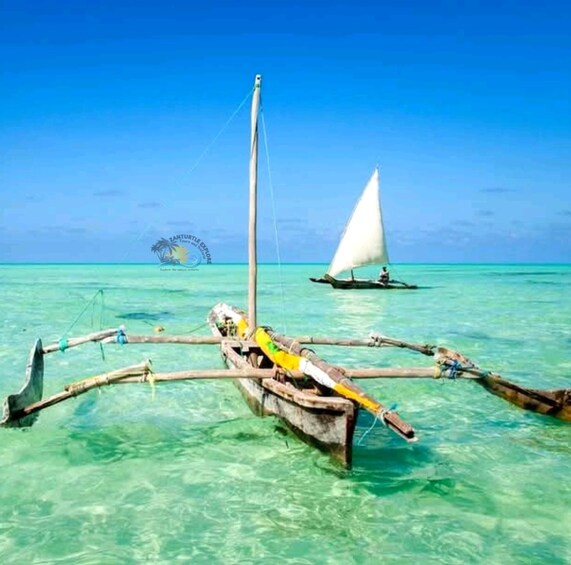 A traditional boat with a sail in clear turquoise waters. 1