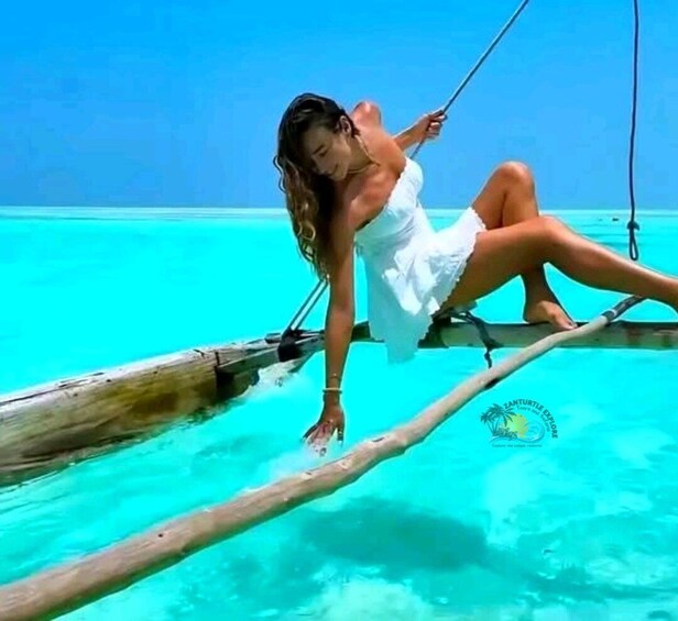 A person in a white dress sitting on a wooden swing over turquoise water. 5