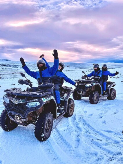 Three people on ATVs in a snowy landscape with a cloudy sky. 1