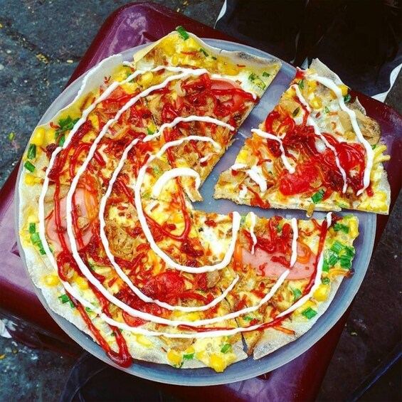 En pizza med pålägg och sås som är arrangerat i ett spiralmönster på en rund plåt. 2