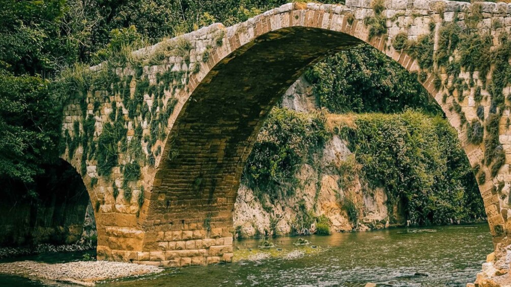 An ancient stone bridge over a river, surrounded by lush greenery. 4