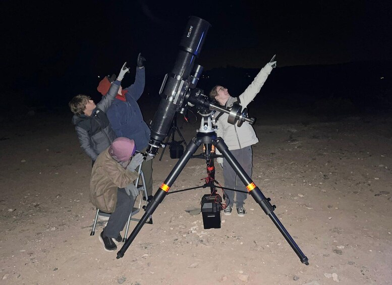 Three people observing through a large telescope on a clear night. 4