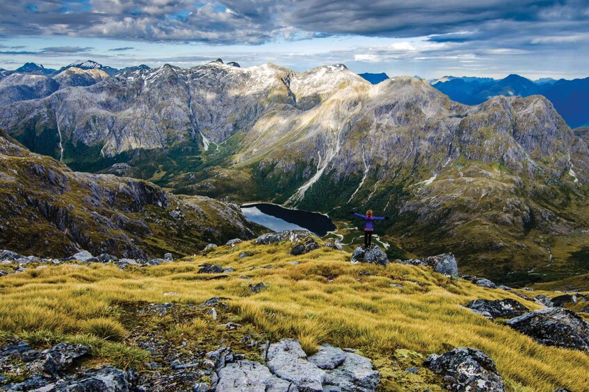 A mountainous landscape with a lake, rocky terrain, and a person standing on a rock. 4