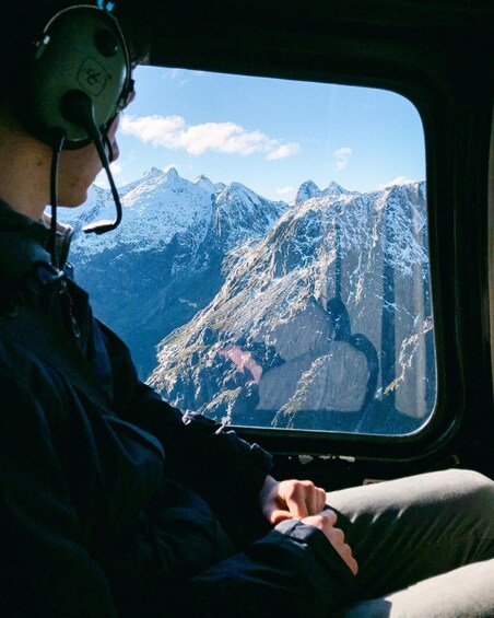 A person in a cockpit with a mountainous landscape visible through the window. 2