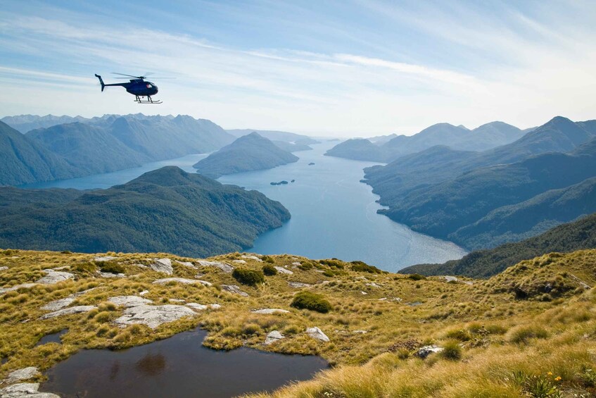 A helicopter flying over a mountainous landscape with a lake below. 3