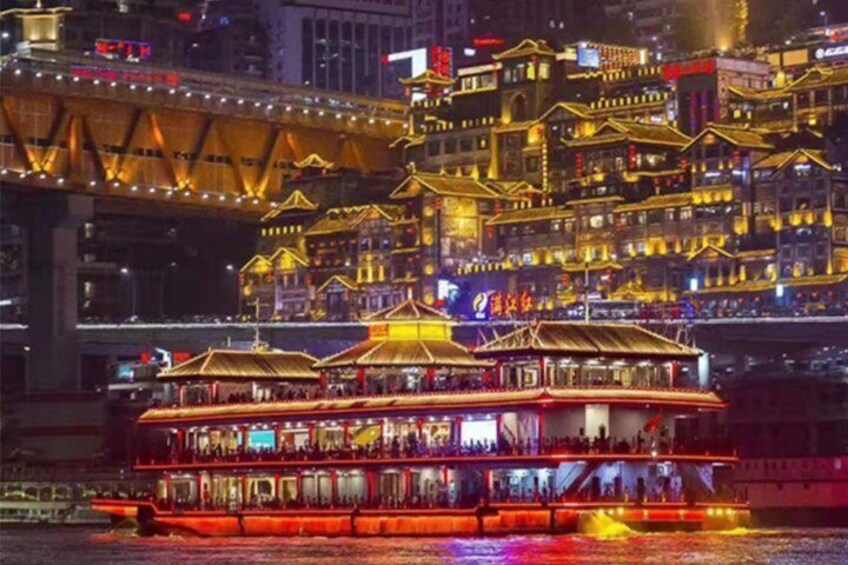 A brightly lit riverboat with multiple decks and traditional architecture, docked at a riverside location with illuminated buildings in the background. 5