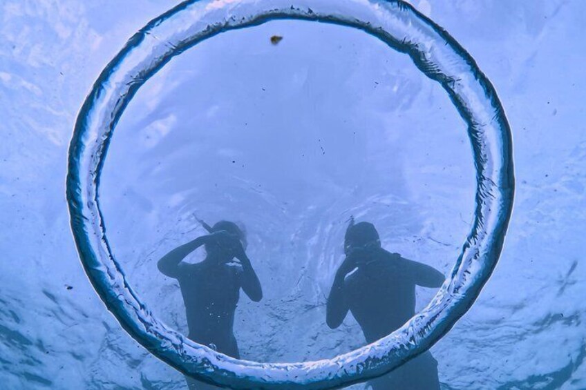 Two people in a circular ice structure with a clear blue sky above. 5