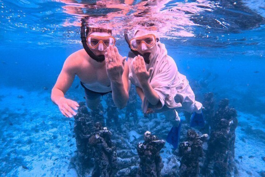Two people snorkeling underwater with coral formations. 3