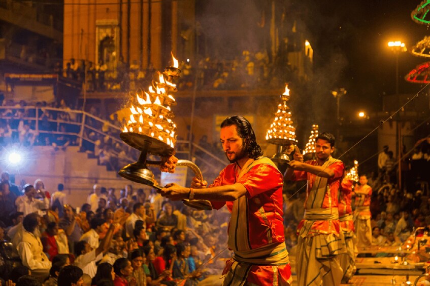 A nighttime outdoor event with people in traditional attire, some holding lit lamps. 2