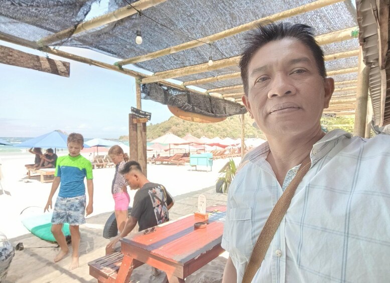 A beach scene with a wooden structure, people, and beach umbrellas. 2