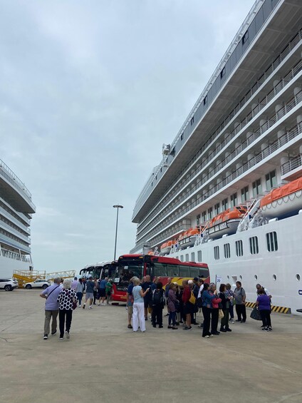 A cruise ship docked with a crowd of people boarding. 4