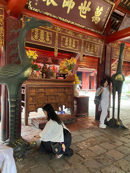 A temple interior with ornate decorations, a statue of an animal, and a person praying. 5