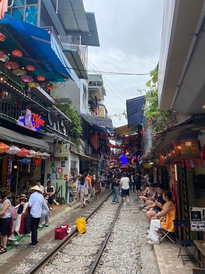 A bustling street with a railway track, shops, and people. 3