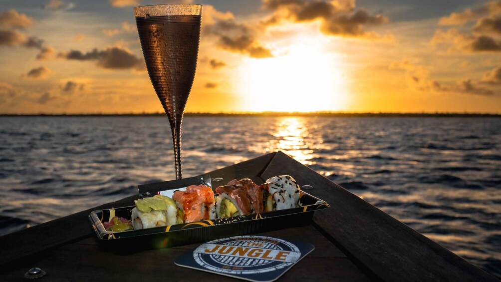 A sushi tray on a boat with a sunset in the background. 1