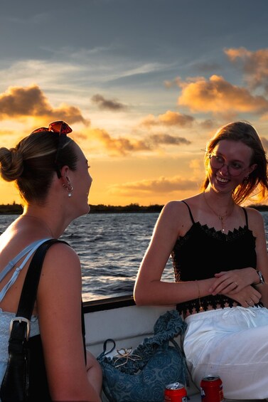 Two people on a boat during sunset with water and a sunset sky in the background. 3