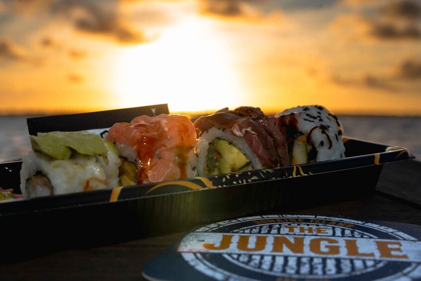 A sushi box with various types of sushi against a sunset backdrop. 2