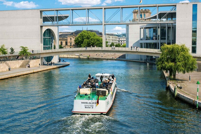 A boat named HAVELGLÜCK on a river with a bridge in the background. 3