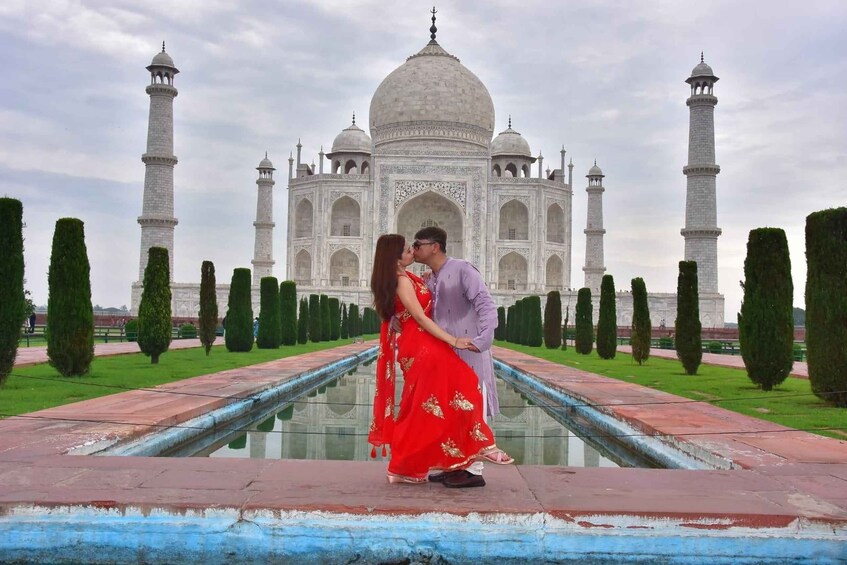Et par omfavner foran Taj Mahal med de ikoniske kupler og minareter. 1