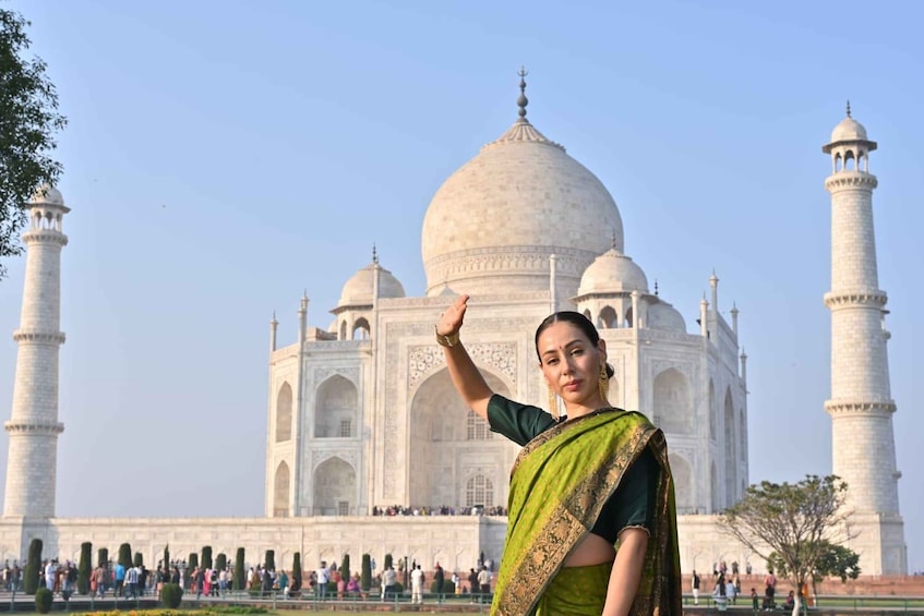 En person i en grøn og sort sari foran Taj Mahal. 3