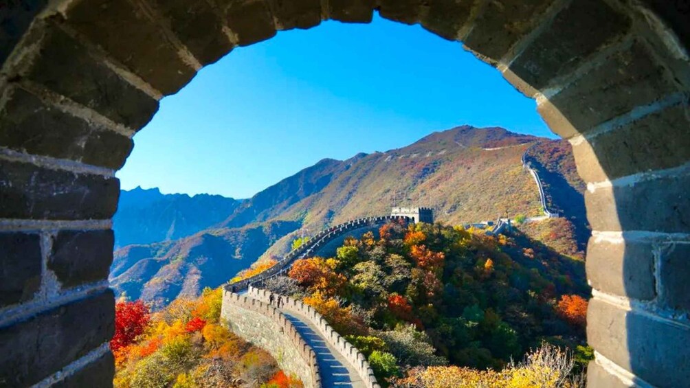 The Great Wall of China, a historic fortification, with autumn foliage and mountainous terrain in the background. 3