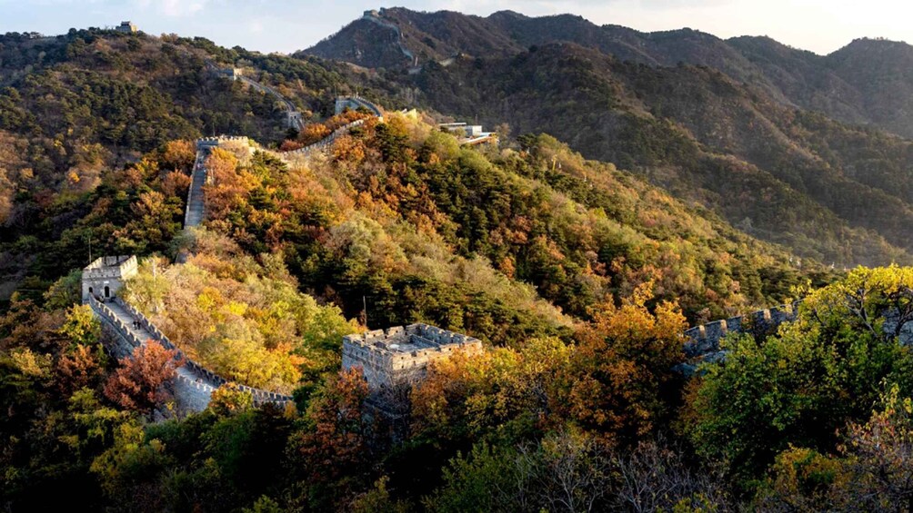 The Great Wall of China winding through a mountainous landscape with autumn foliage. 1