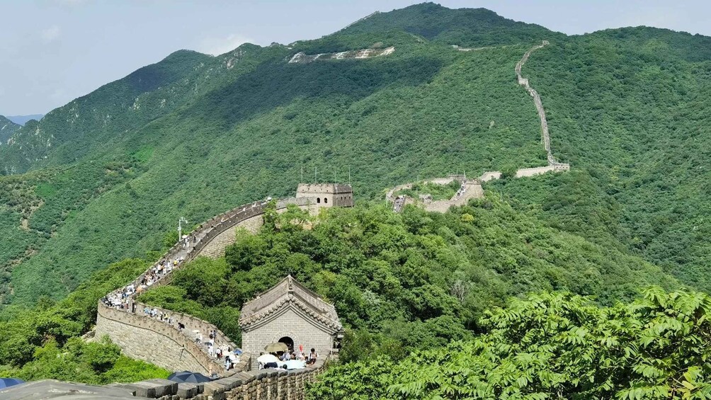 The Great Wall of China winding through lush green mountains. 4