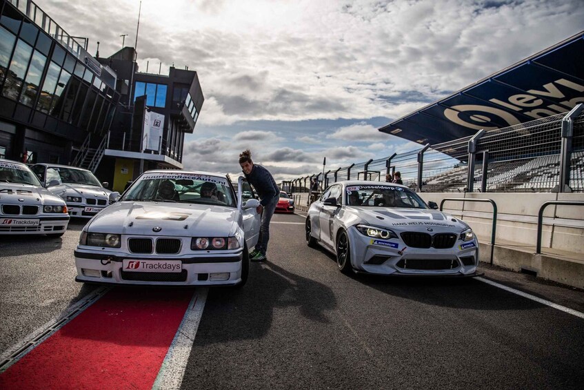 A race track with two white BMW cars, a person in the background, and a blue structure with 'Levi' written on it. 4