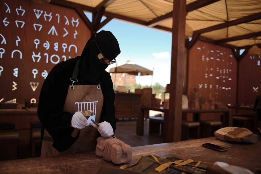 A person carving a wooden sculpture in a workshop with tools and a carving board. 5