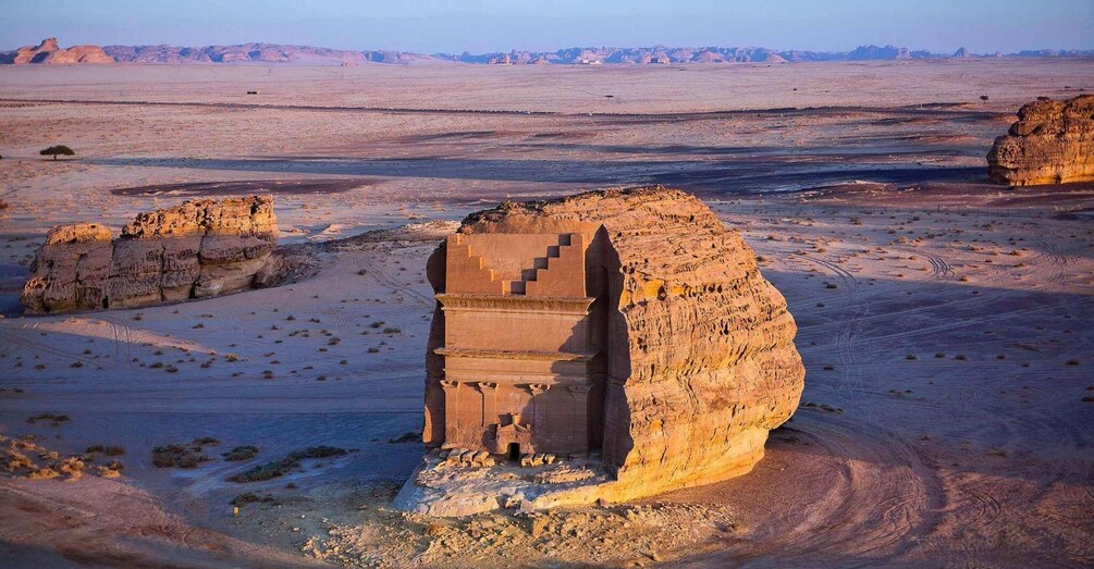 A desert landscape with a prominent rock formation featuring a staircase. 1