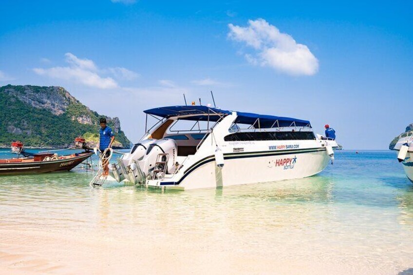 A boat named 'HAPPY' docked at a beach with clear water and a mountainous backdrop. 2