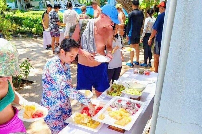 A group of people at an outdoor buffet with various dishes. 4