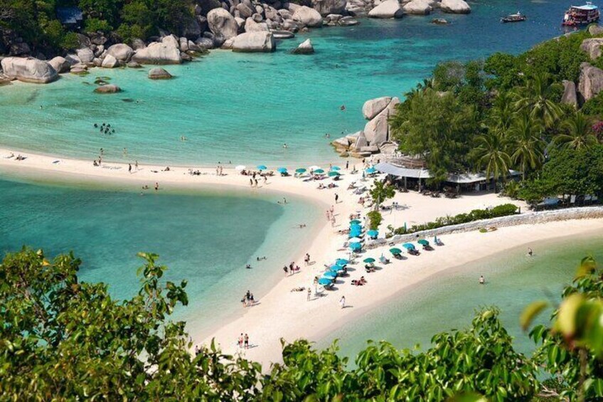 A tropical beach with clear turquoise waters, white sand, and scattered rocks. 1
