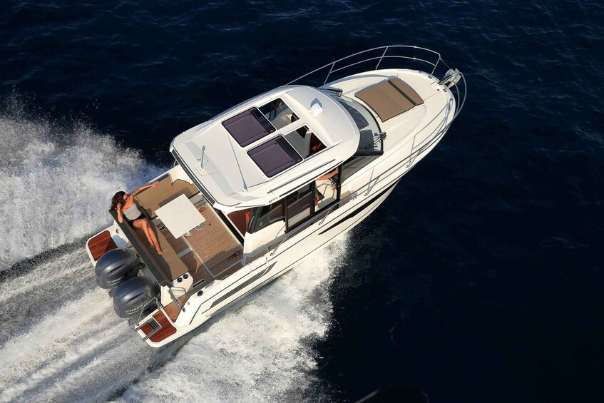 A white motor yacht with a cabin, seating, and two outboard engines. 2