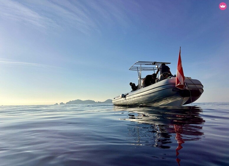A boat with a red sail on calm water, a clear sky, and distant landforms. 2