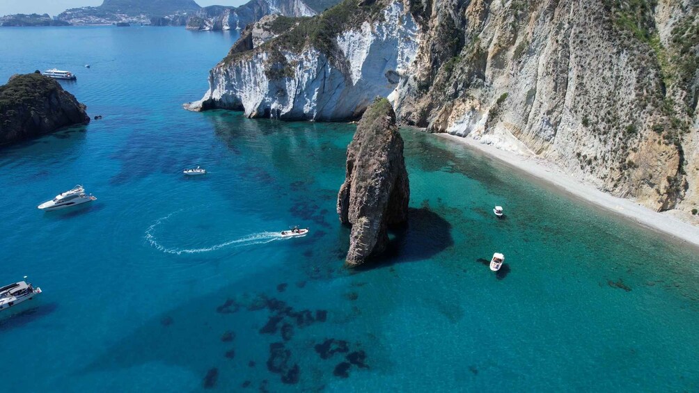 A coastal area with clear turquoise waters, rocky cliffs, and several boats. 5
