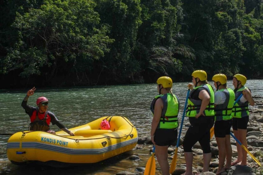 A group of people in yellow life vests and helmets on a river, with one person in a yellow inflatable raft. 1