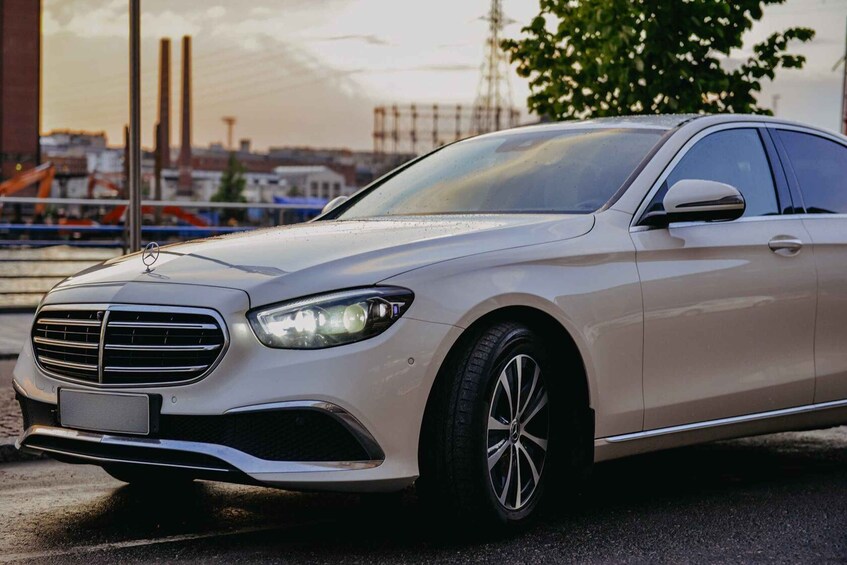 A silver Mercedes-Benz car parked on a street with industrial buildings and a crane in the background. 5
