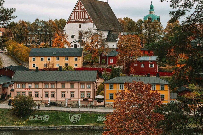 A town with a prominent white church with a green dome, surrounded by colorful houses and a river. 2