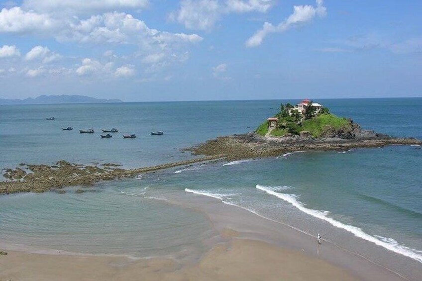 A coastal scene with a sandy beach, calm sea, boats, and a small island with a building. 5