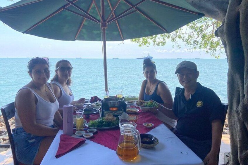 A group of people dining at a table with a view of the sea. 4