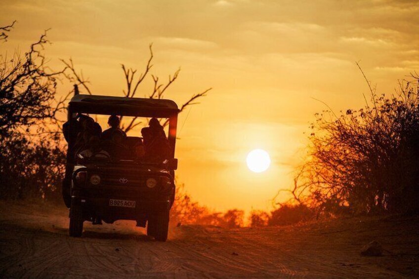 A vehicle on a dirt road with the sun setting in the background. 5