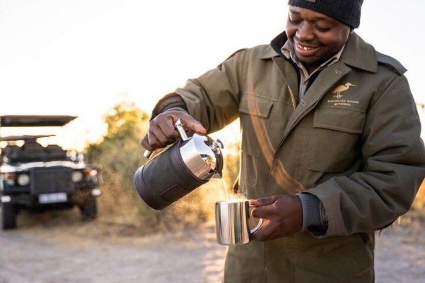 A person pouring a liquid from a thermos into a metal cup. 3