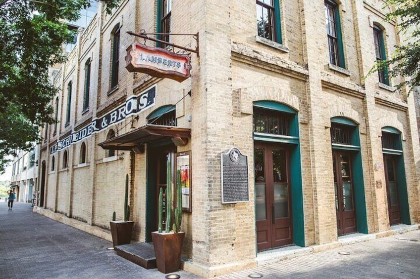 A historic building with a sign reading 'SCHULER & BROS.' and a plaque on the wall. 3