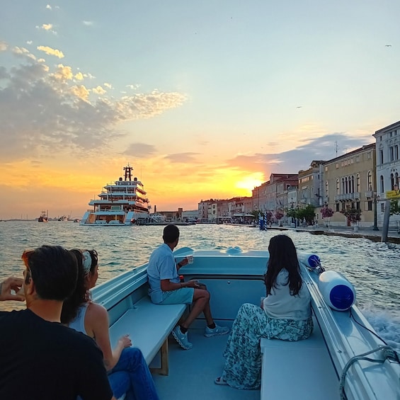 A sunset over a waterfront with a boat and buildings along the shore. 2