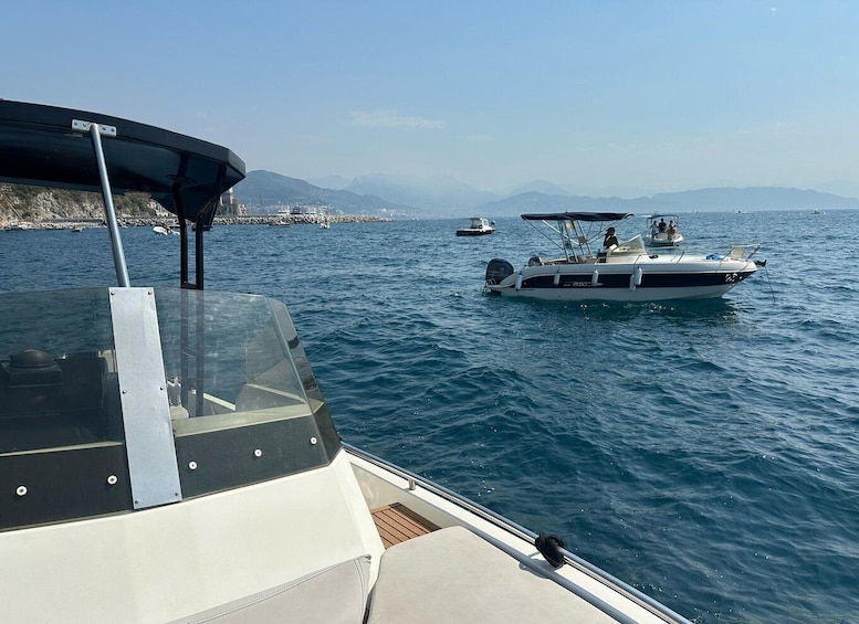 A boat on calm waters with distant mountains and other boats in the background. 4