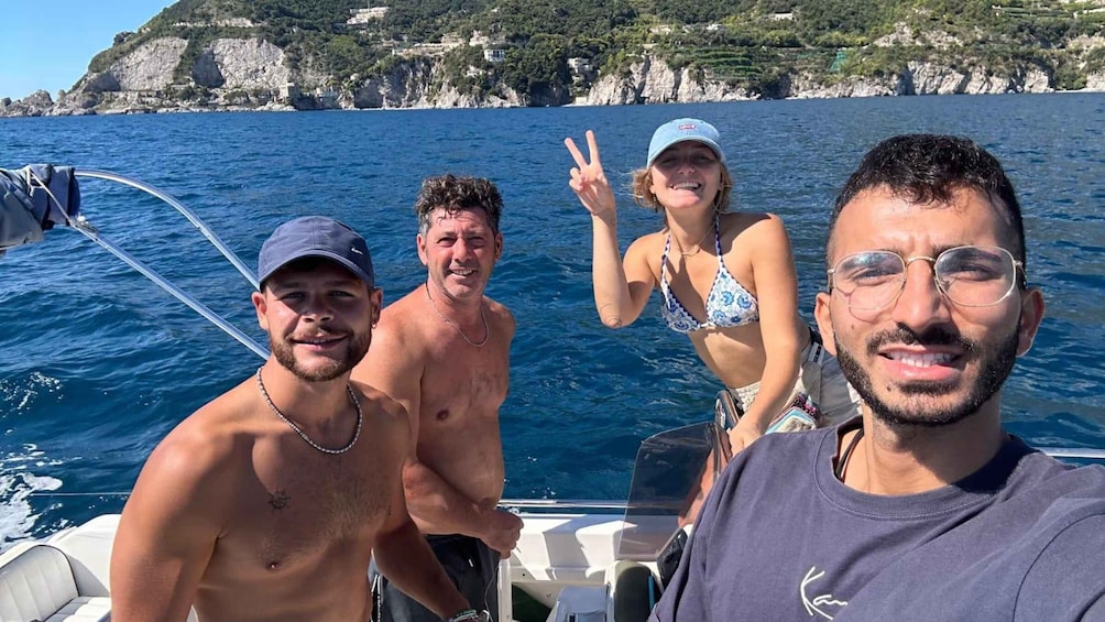 A group of people on a boat with a coastal landscape in the background. 3