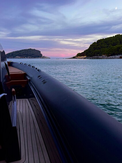 A boat's deck with a view of calm water and a distant shoreline with trees and a hill. 2