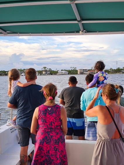 A group of people on a boat, looking out at a body of water with buildings in the background. 3