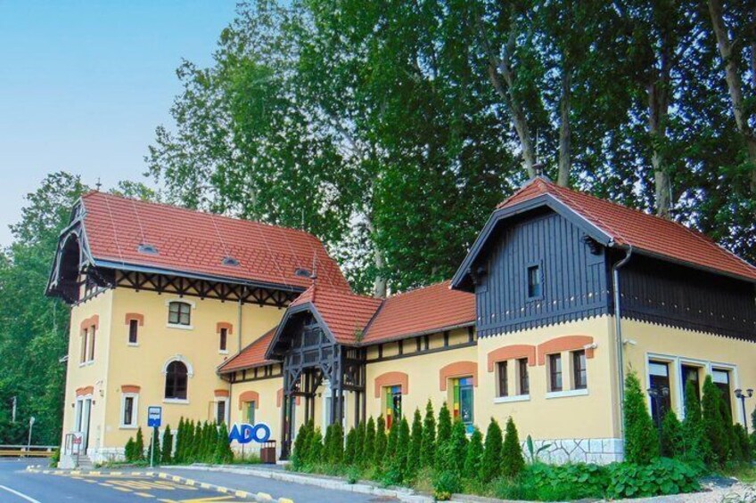 A building with a red roof and yellow walls, surrounded by greenery. 2